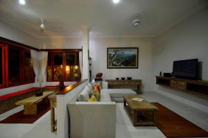Una sala de estar con un sofá y un televisor. en Villa Santai Karangasem, en Tirtagangga