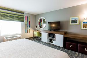 Habitación de hotel con cama y escritorio con TV. en Hampton Inn Bismarck, en Bismarck