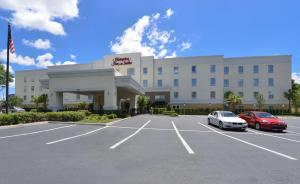 ein großes Gebäude mit Autos auf einem Parkplatz in der Unterkunft Hampton Inn & Suites - Ocala in Ocala