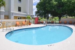 a large swimming pool with chairs and a building at Hampton Inn & Suites - Ocala in Ocala