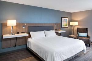 a bedroom with a large white bed and a chair at Hilton Garden Inn Halifax Airport in Enfield