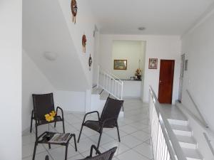 a white hallway with chairs and a staircase at Pousada CERTRI in Triunfo