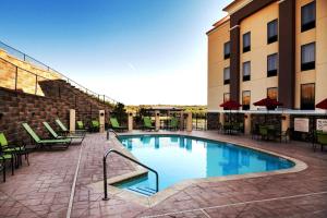 a swimming pool with tables and chairs next to a building at Hampton Inn & Suites Tulsa/Tulsa Hills in Tulsa