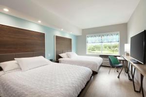 a bedroom with two beds and a desk and a window at Tru By Hilton Lake Charles in Lake Charles