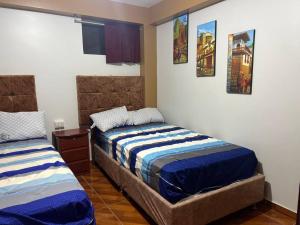 a bedroom with two beds and pictures on the wall at Cuzco A 5 min del centro histórico¡Apartamento completo! in Cusco
