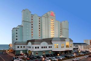 ein großes Gebäude mit Autos auf einem Parkplatz in der Unterkunft Hilton Suites Ocean City Oceanfront in Ocean City