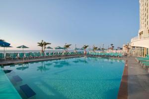 ein großer Pool mit Stühlen und ein Gebäude in der Unterkunft Hilton Suites Ocean City Oceanfront in Ocean City