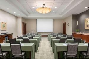 una sala de conferencias con mesas verdes y sillas y una pantalla de proyección en Hilton Suites Ocean City Oceanfront en Ocean City