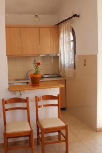 cocina con 2 sillas y encimera con fregadero en Sunset Beach Studio, en Kremasti