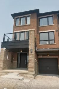 a brick house with a balcony and two garage at Beautiful, 4brd-3bthTownhome 7mins to Lakeshore in Barrie