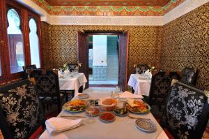 Palais Riad Reda & Spa في فاس: غرفة طعام مع طاولة مع أطباق من الطعام