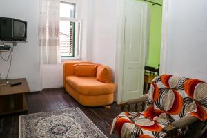 sala de estar con silla naranja y TV en Apartments Martinetti, en Herceg-Novi