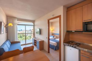 a kitchen with a table and chairs and a refrigerator at Apartamentos Dorada Palace in Salou