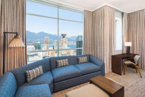 a living room with a blue couch and a large window at Hilton Vancouver Downtown, BC, Canada in Vancouver