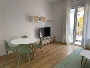 a living room with a table and chairs and a tv at Gaudi Street Apartments in Sitges