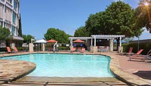 a swimming pool with chairs and tables and a building at Hilton Austin Airport in Austin