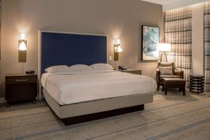 a bedroom with a large bed and a chair at Hilton Austin Airport in Austin