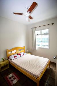 a bedroom with a bed with a ceiling fan and a window at NOVIDADE Apto na Praia do Morro em Guarapari ES in Guarapari