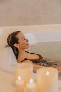 Una donna seduta in una vasca da bagno con candele di Amaike Hotel Golf & Spa a Tandil