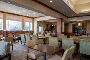 un restaurante con mesas, sillas y ventanas en Hilton Garden Inn Boise / Eagle, en Eagle