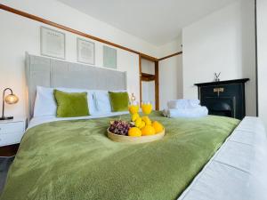 a bed with a bowl of fruit on it at Lovely 4 Bed, Family & Contractors Luton Airport & M1 by Properties2you in Luton