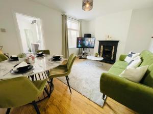 sala de estar con mesa, sillas y TV en Lovely 4 Bed, Family & Contractors Luton Airport & M1 by Properties2you, en Luton