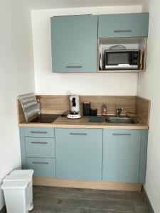 a kitchen with blue cabinets and a sink and a microwave at Studio 2 pers avec vue sur l'océan in Lacanau +15 photos