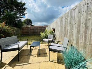 a patio with three benches and a fence at Lovely 4 Bed, Family & Contractors Luton Airport & M1 by Properties2you in Luton