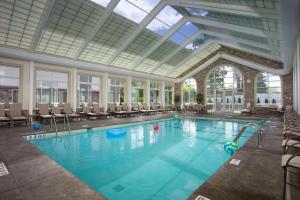 una gran piscina con sillas y techo de cristal. en DoubleTree by Hilton Nanuet, en Nanuet