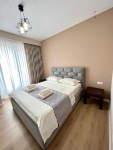 1 dormitorio con 1 cama grande con sábanas blancas en George apartments2023, en Korçë