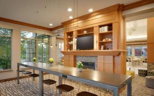 Il comprend un grand salon avec une table et une télévision. dans l'établissement Hilton Garden Inn Salt Lake City/Sandy, à Sandy
