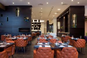 Hilton Suites Toronto-Markham Conference Centre & Spa في ماركهام: غرفة طعام مع طاولات وكراسي برتقالية