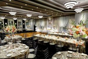 マーカムにあるHilton Suites Toronto-Markham Conference Centre & Spaの長いテーブルと椅子と花の咲く宴会場