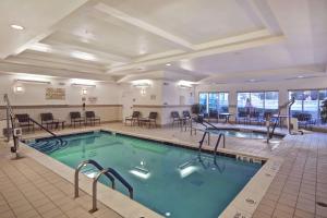 einen Pool in einem Hotel mit Tischen und Stühlen in der Unterkunft Hilton Garden Inn Riverhead in Riverhead