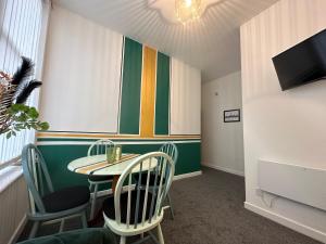 um quarto com uma mesa e cadeiras e uma televisão em Emerald Apartment Pleasure Beach Blackpool em Blackpool