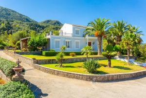 a large white house with palm trees and mountains at Villa Golden Tiara Large Private Pool AC WiFi in Corfu