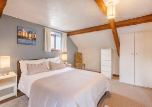 a bedroom with a white bed and a window at Dairy Cottage in Swimbridge