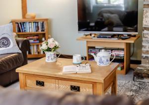 a living room with a coffee table with flowers on it at Dairy Cottage in Swimbridge