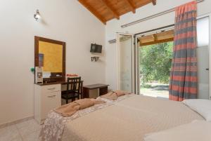 a bedroom with a bed and a desk and a window at Villa Popi in Roda +11 photos