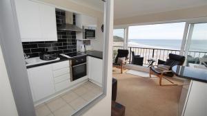 a kitchen and a living room with a view of the ocean at 9_304 Redcliffe Apartments, Caswell Bay in Bishopston