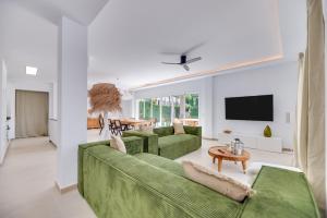a living room with a green couch and a tv at VB Higueron 4BDR Villa w Pool, Cinema & Ping pong in Benalmádena