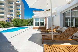 a patio with chairs and an umbrella next to a pool at VB Higueron 4BDR Villa w Pool, Cinema & Ping pong in Benalmádena