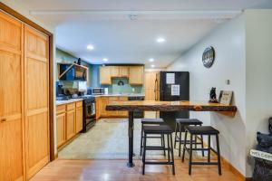 una cucina con armadi in legno e bancone con sgabelli da bar di Brantingham Cottage with Fire Pit and Forested Views! a Glenfield