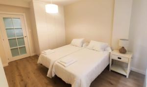 a bedroom with a large white bed with a night stand at La Palentina in Palencia