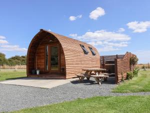 a wooden cabin with a picnic table and a bench at Husk in Harpham