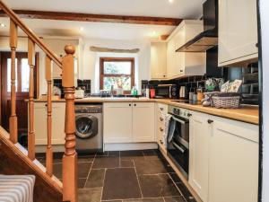 a kitchen with white cabinets and a dishwasher at Willow Cottage in Clitheroe
