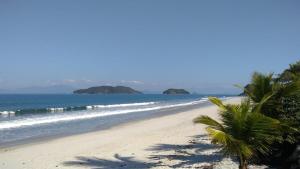 ein Strand mit Palmen und dem Meer in der Unterkunft Casa Temporada Prainha de Mambucaba Paraty RJ in Paraty