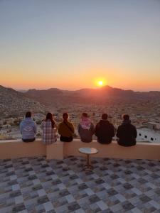 a group of people sitting on a ledge watching the sunset at Cozy House in Wadi Musa
