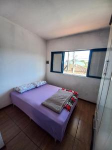 a small bedroom with a purple bed and a window at Recanto Boa Vista in Joinville