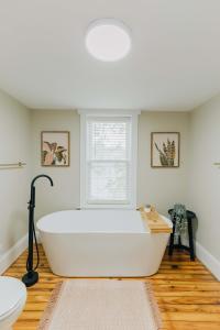 a white bath tub in a bathroom with a window at Quaint Boho Home in Lancaster City in Lancaster